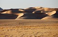 Les premières dunes, dorées par le soleil déclinant, apparaissent à l'horizon... erg,admer,tassili,n ajjer,algerie. 