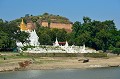 En arrière plan, on aperçoit la pagode inachevée de Mingun, commencée en 1790, sous le règne du roi Bodowpaya et qui devait être le plus grand stupa du monde. D'une hauteur de 153 mètres, elle devait accueillir une dent de Bouddha, cadeau des Chinois. Pendant la construction, une prophétie annonça que le pays serait ruiné à l'achèvement de la pagode. Les travaux furent interrompus. On peut voir aujourd'hui, ce qui reste de ce monument, après les effets du tremblement de terre de 1838... mingun,pagode,inachevee,myanmar,birmanie. 